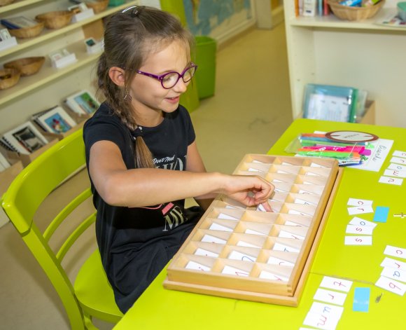 A girl working with Montessori materials in a Montessori classroom